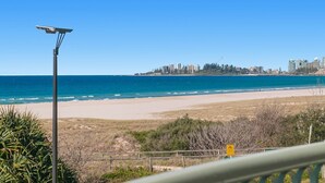 A beach with a solar street light, a sign indicating a bike path, and a city skyline in the background. - Golden Sea 12 - Absolute Beachfront Bilinga - Min. 3 Night Stays! (Bilinga)