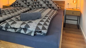 A bed with geometric-patterned bedding, a wooden headboard, and a wall-mounted abstract painting. - Zentral & Ruhig im Ortskern von Bad Rothenfelde (Bad Rothenfelde)