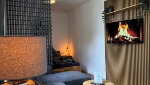 A modern living room with a flat-screen TV mounted on a wooden wall, a sofa, a coffee table, and a lamp. - Zentral & Ruhig im Ortskern von Bad Rothenfelde (Bad Rothenfelde)