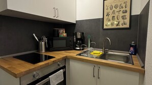 A compact kitchen with a black stove, a coffee maker, and a sink. - Zentral & Ruhig im Ortskern von Bad Rothenfelde (Bad Rothenfelde)