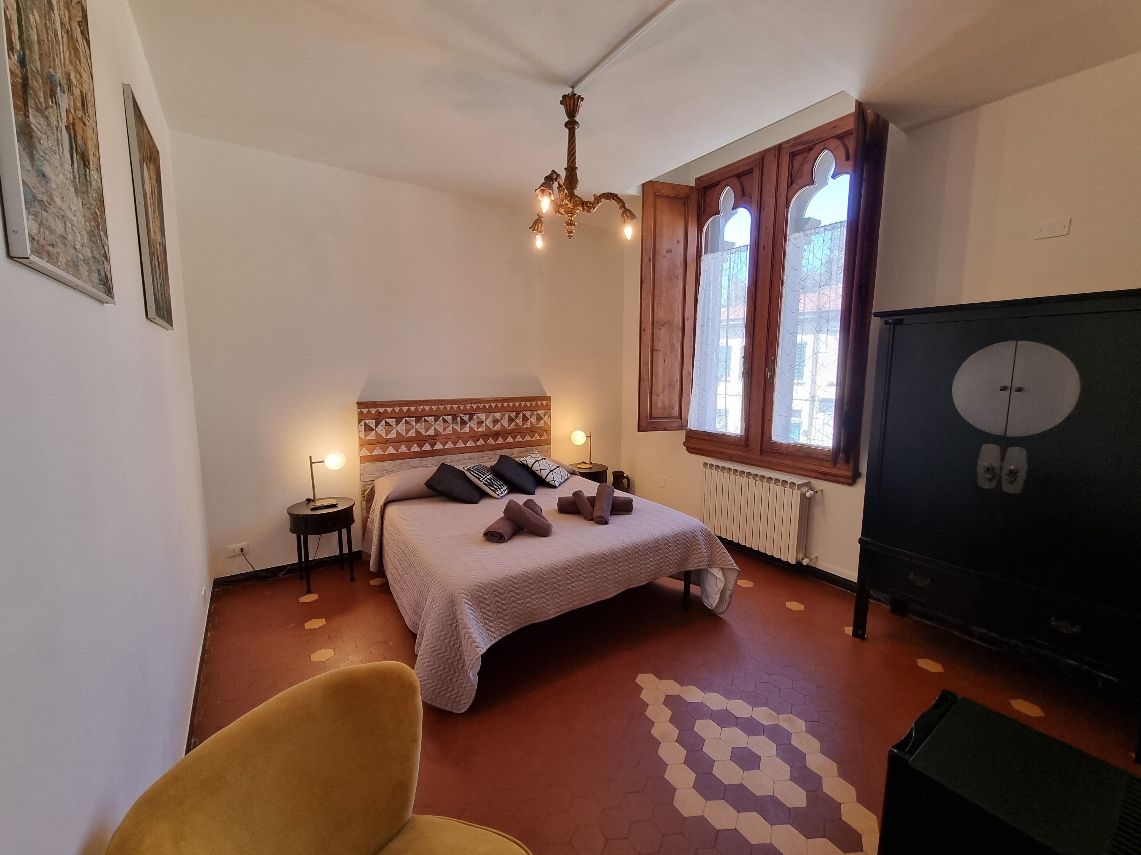 Un dormitorio con cama, mesita de noche, lámpara, radiador y armario.