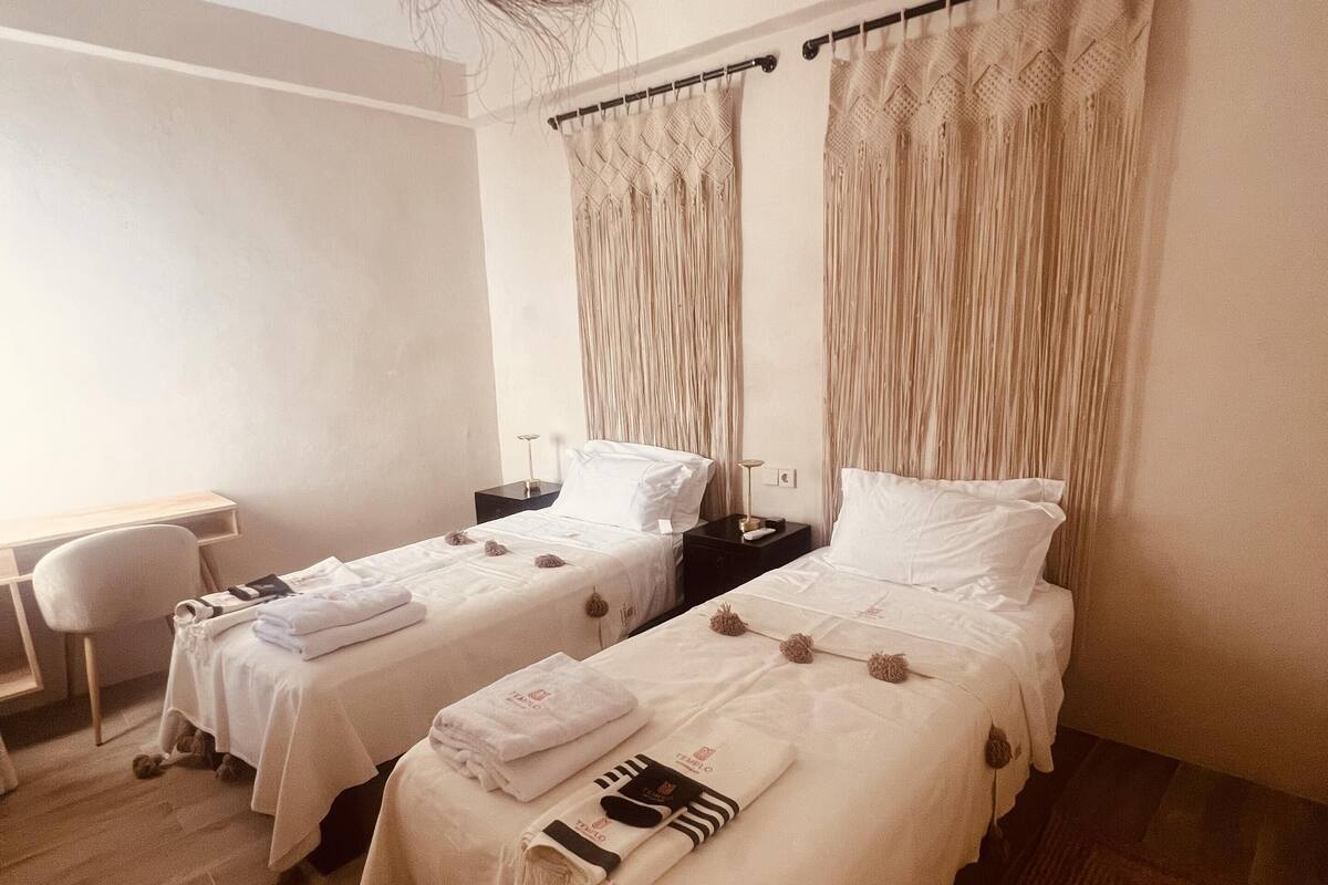 A hotel room with two beds, a desk, and a chair.