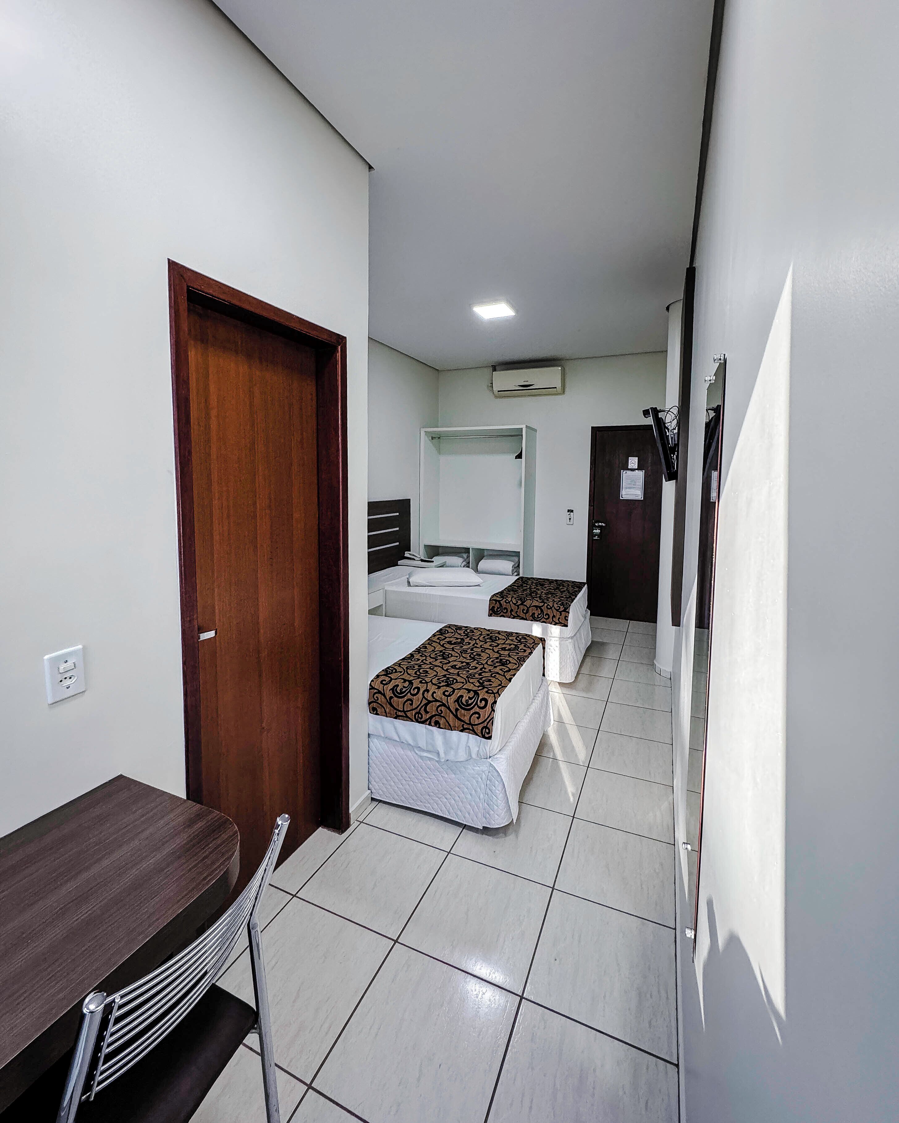 A hotel room with two beds, a desk, and a chair.