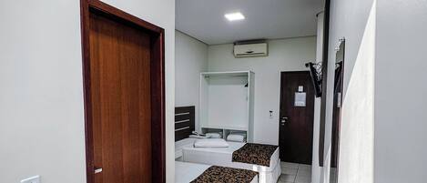 A hotel room with two beds, a desk, and a chair.