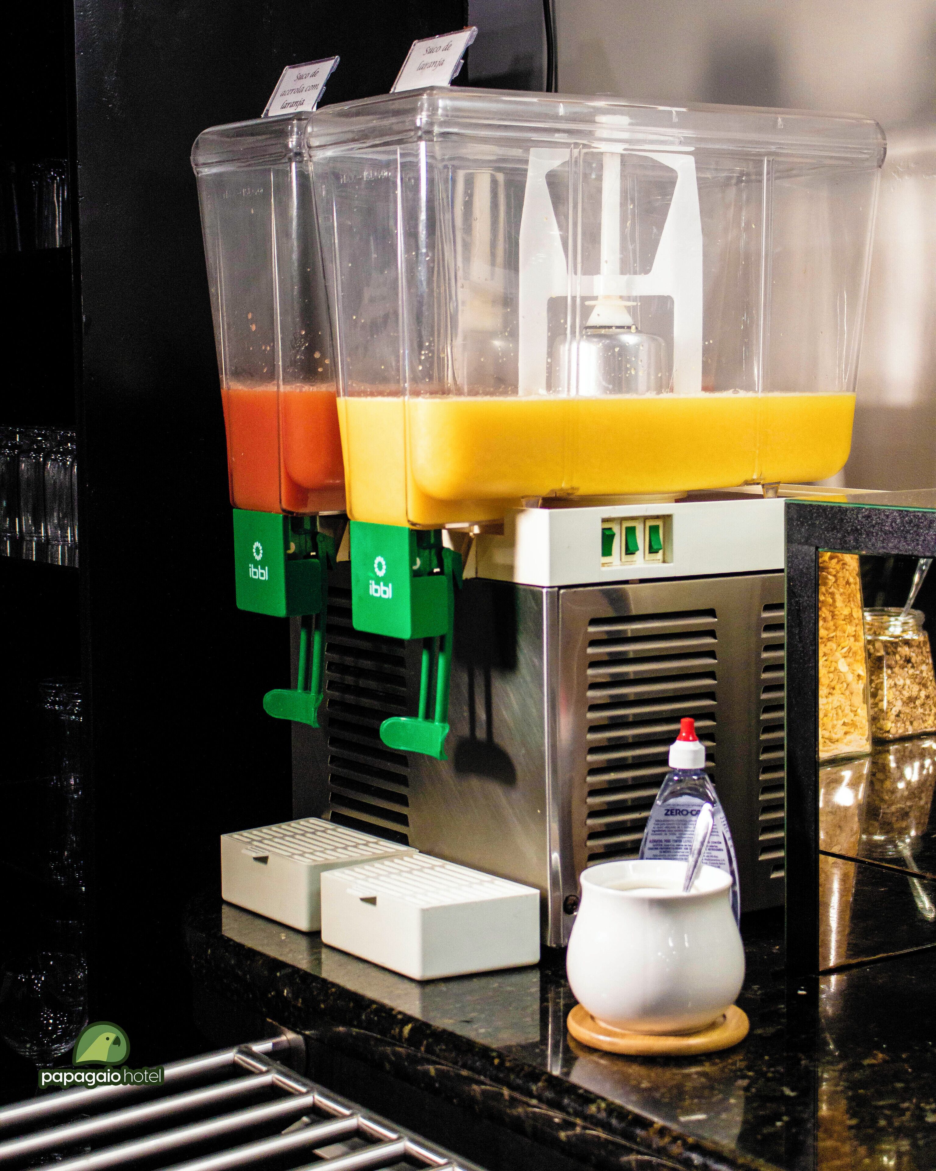 A juice dispenser with multiple containers, a water bottle, and a coffee machine on a counter.