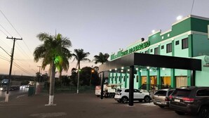 Hotel com fachada verde e área de entrada coberta.