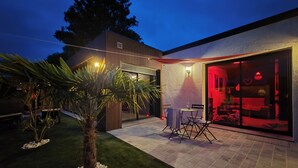 Una casa moderna con un patio, zona de comedor y garaje con luz interior roja.