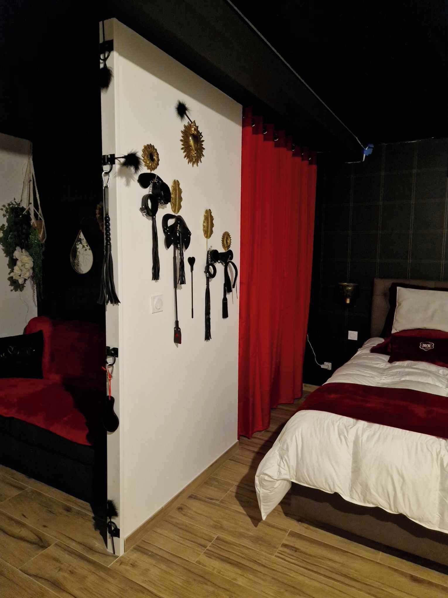 Quarto com cama, cortina vermelha e decorações na parede.