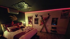 Un dormitorio con cama, espejo, estante en la pared y una silla.