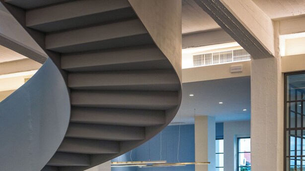 Un intérieur moderne agrémenté d’un escalier en colimaçon, de coins salon et d’un espace repas.