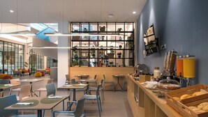 Un café moderne avec un comptoir central, un espace salon et un présentoir de pâtisseries.