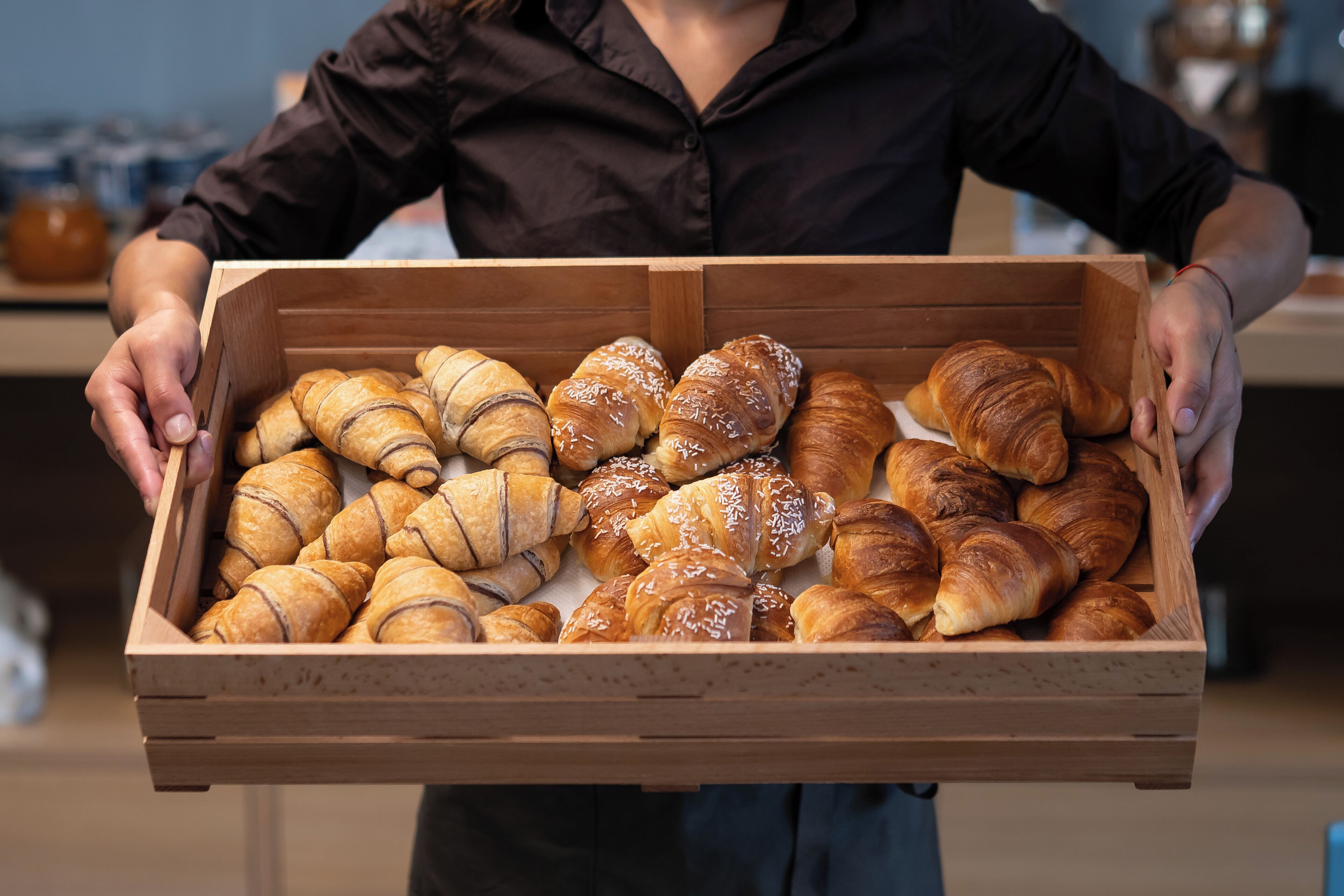 Un vassoio di legno con diversi tipi di croissant.