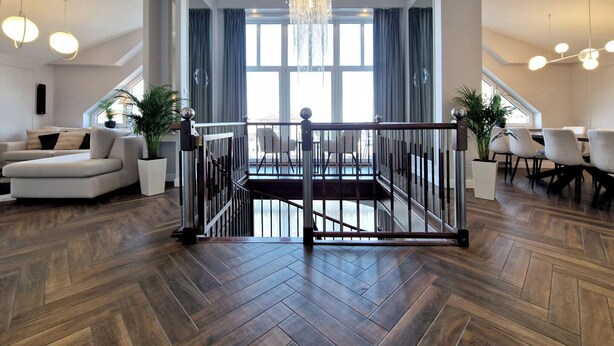 A spacious living area with a modern chandelier, a dining area with a staircase, and a view through large windows. - Baltic Home (Swinoujscie)