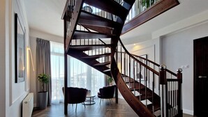 A modern interior with a spiral staircase, wooden flooring, and a seating area with two chairs. - Baltic Home (Swinoujscie)
