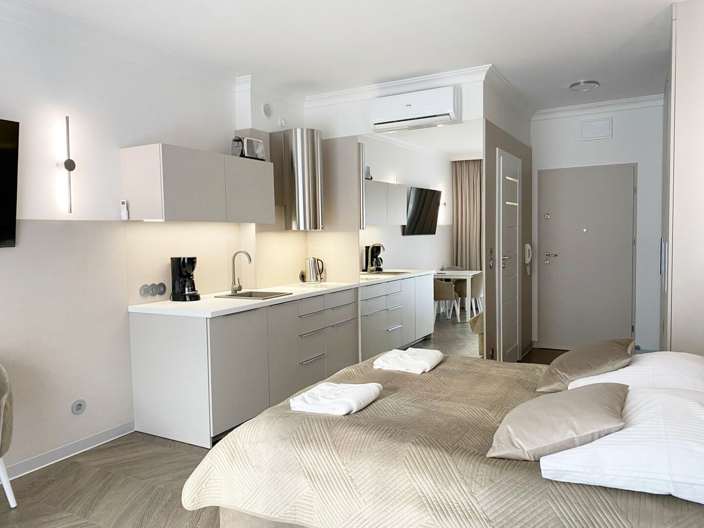 Una habitación de hotel moderna con una cama grande, kitchenette, televisor de pantalla plana y baño.