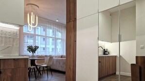 A modern kitchen with wooden cabinets, a dining area with a table and chairs, and a large window providing natural light. - Baltic Home (Swinoujscie)