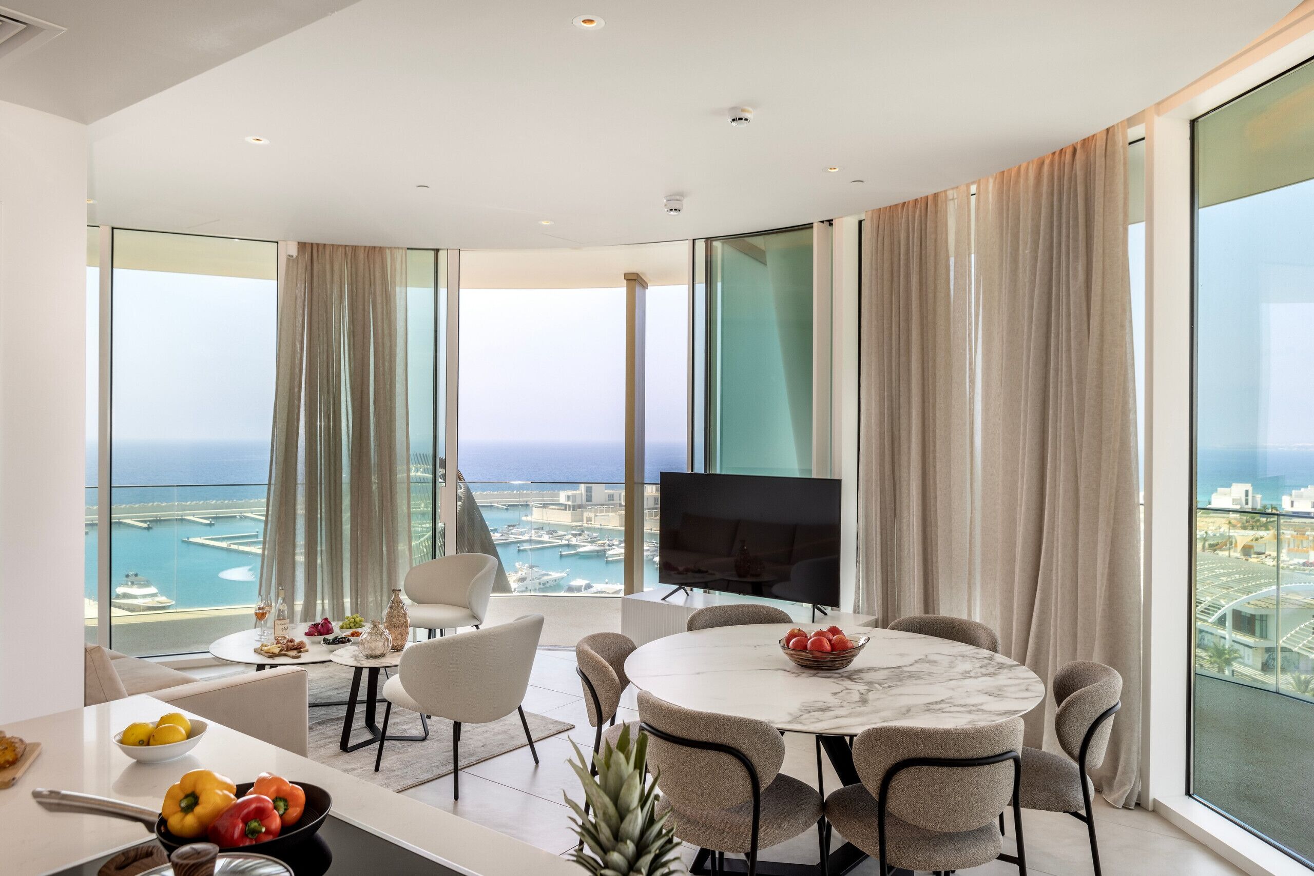 A modern dining area with a round table, chairs, and a TV.