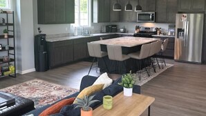 A modern kitchen with dark cabinets, a central island, and pendant lighting. - Brand New Home On Beautiful Blackthorn Golf Club (South Bend)