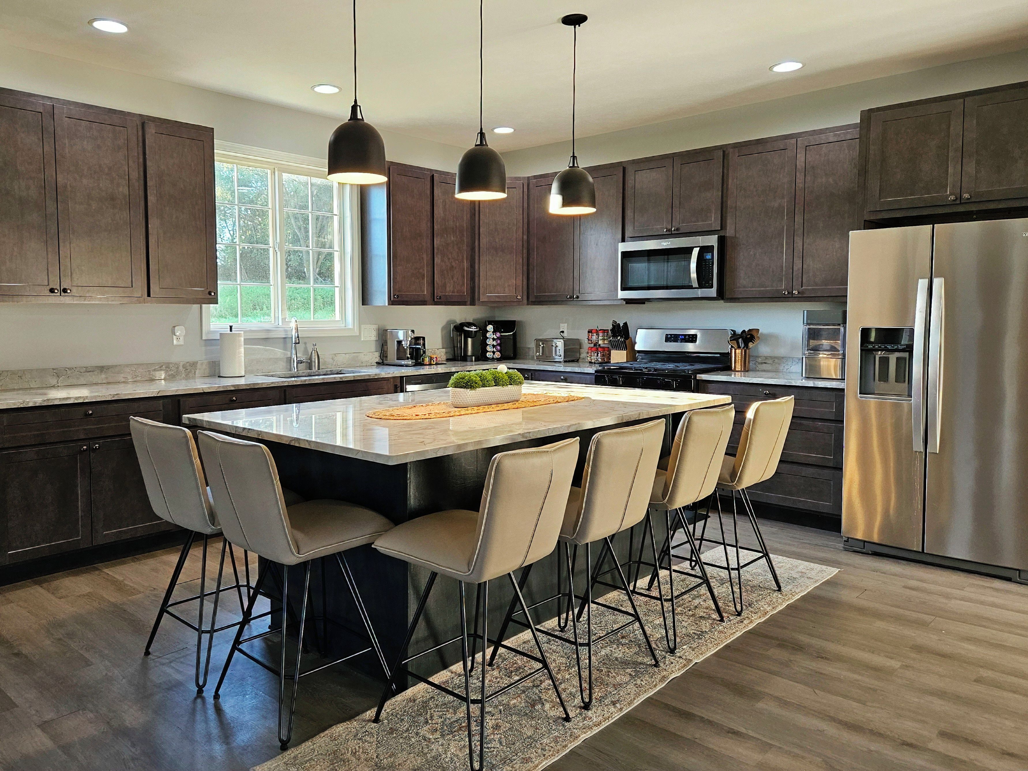 A modern kitchen with dark wood cabinets, stainless steel appliances, and a central island with bar stools.
