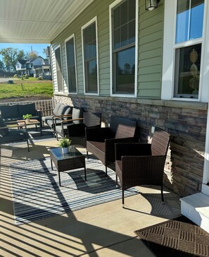 Ein überdachter Patio-Bereich mit Gartenmöbeln, darunter Stühle und ein Tisch, sowie eine Steinmauer.