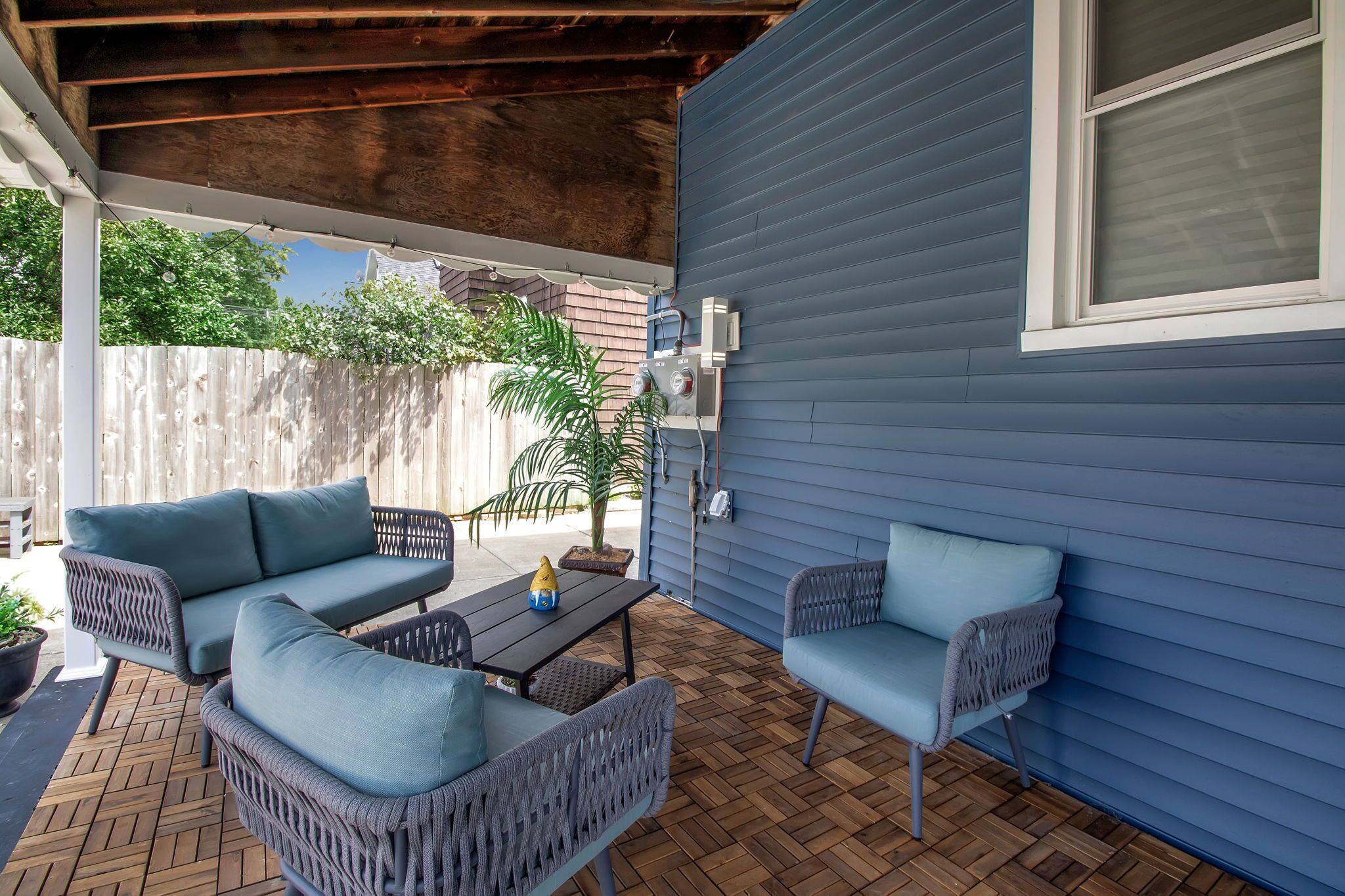 A covered patio with wicker furniture, a small table, and a potted plant.