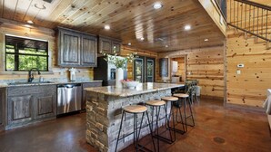 A spacious kitchen with a large island, stone countertops, and bar stools.