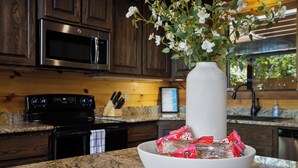 A kitchen with wooden cabinets, a microwave, a stove, and a vase with flowers on the counter.
