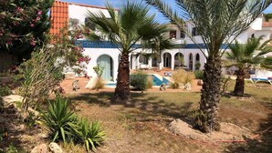 A courtyard with palm trees, a pool, and a building with arches. - Charming Villa Son Parc (Son Parc)