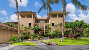 Un hotel de dos pisos con fachada simétrica, una entrada central y un jardín bien cuidado con palmeras y plantas tropicales.