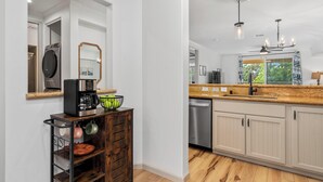 Una cocina moderna con encimera de madera, electrodomésticos de acero inoxidable y lavavajillas integrado.