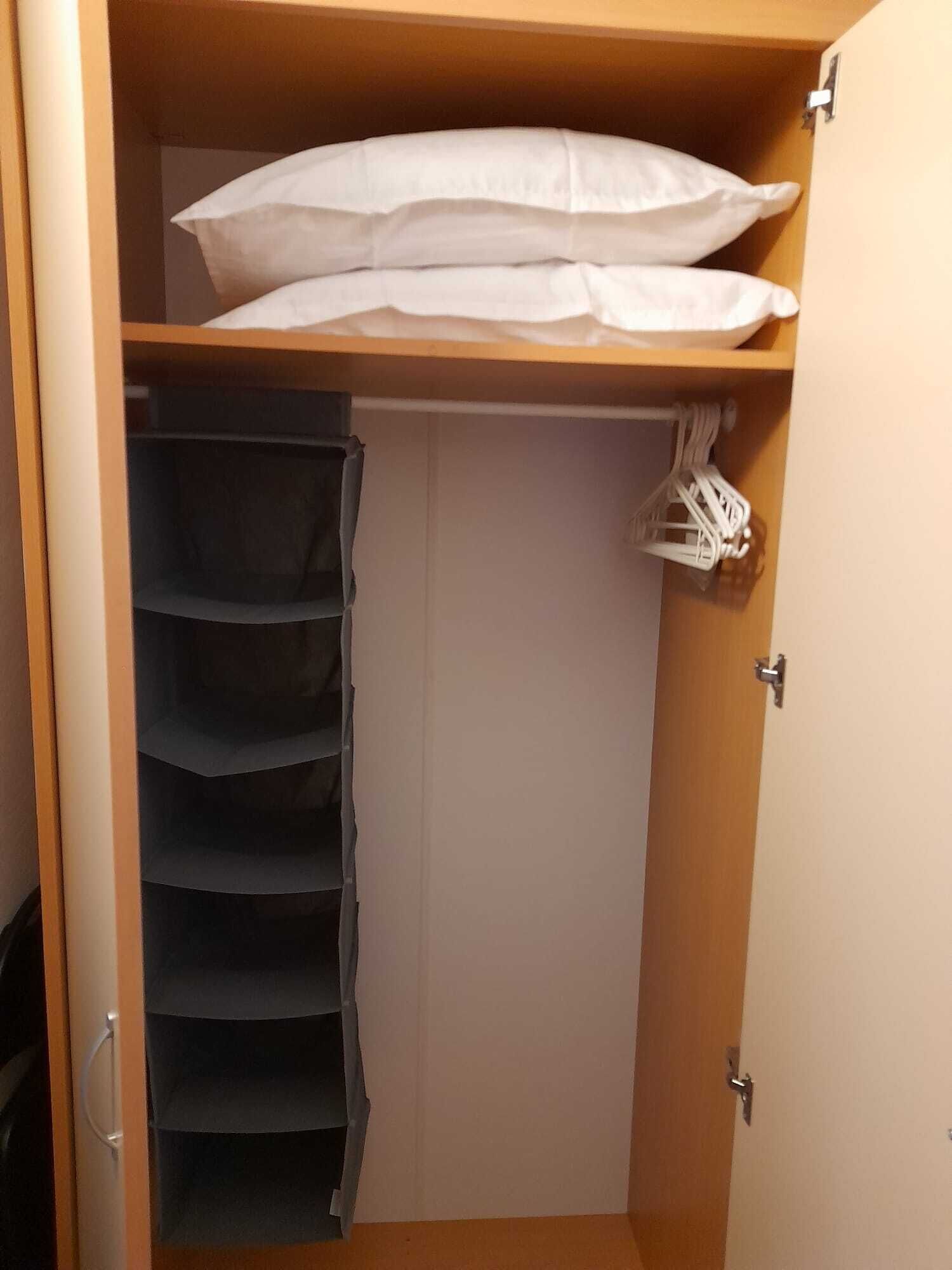 A closet with multiple shelves, a hanging rack, and a door.