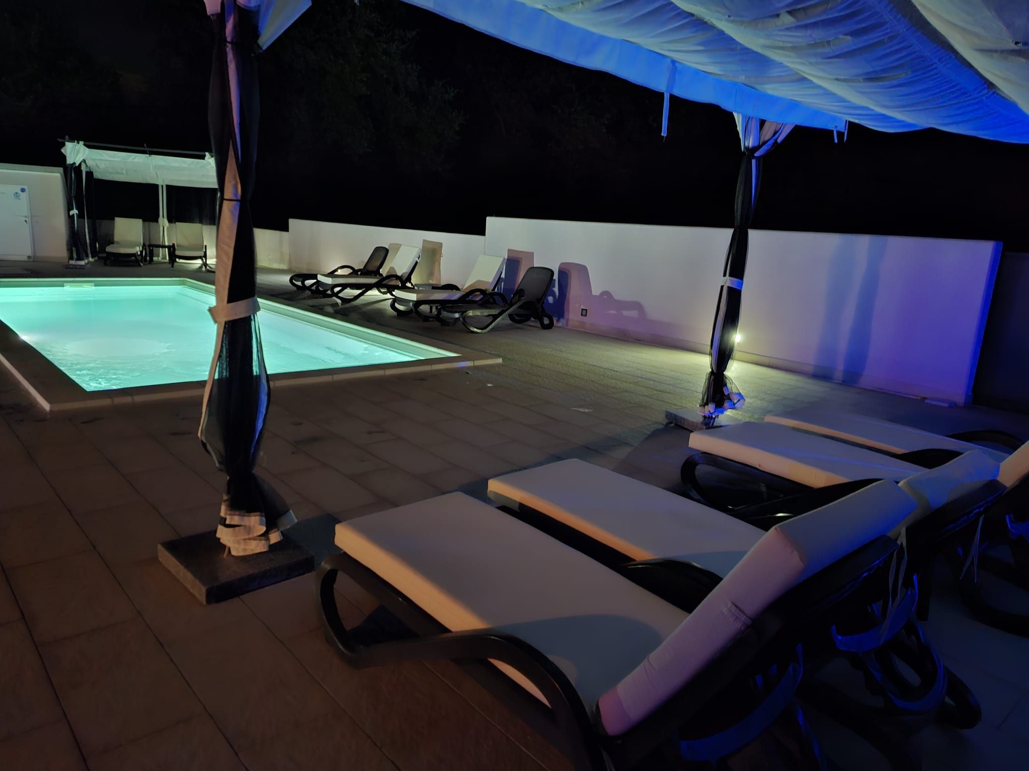 A poolside area with sun loungers and a hot tub.