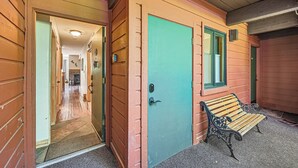 Un edificio in legno con una porta color verde acqua, una panchina e un corridoio interno visibile.