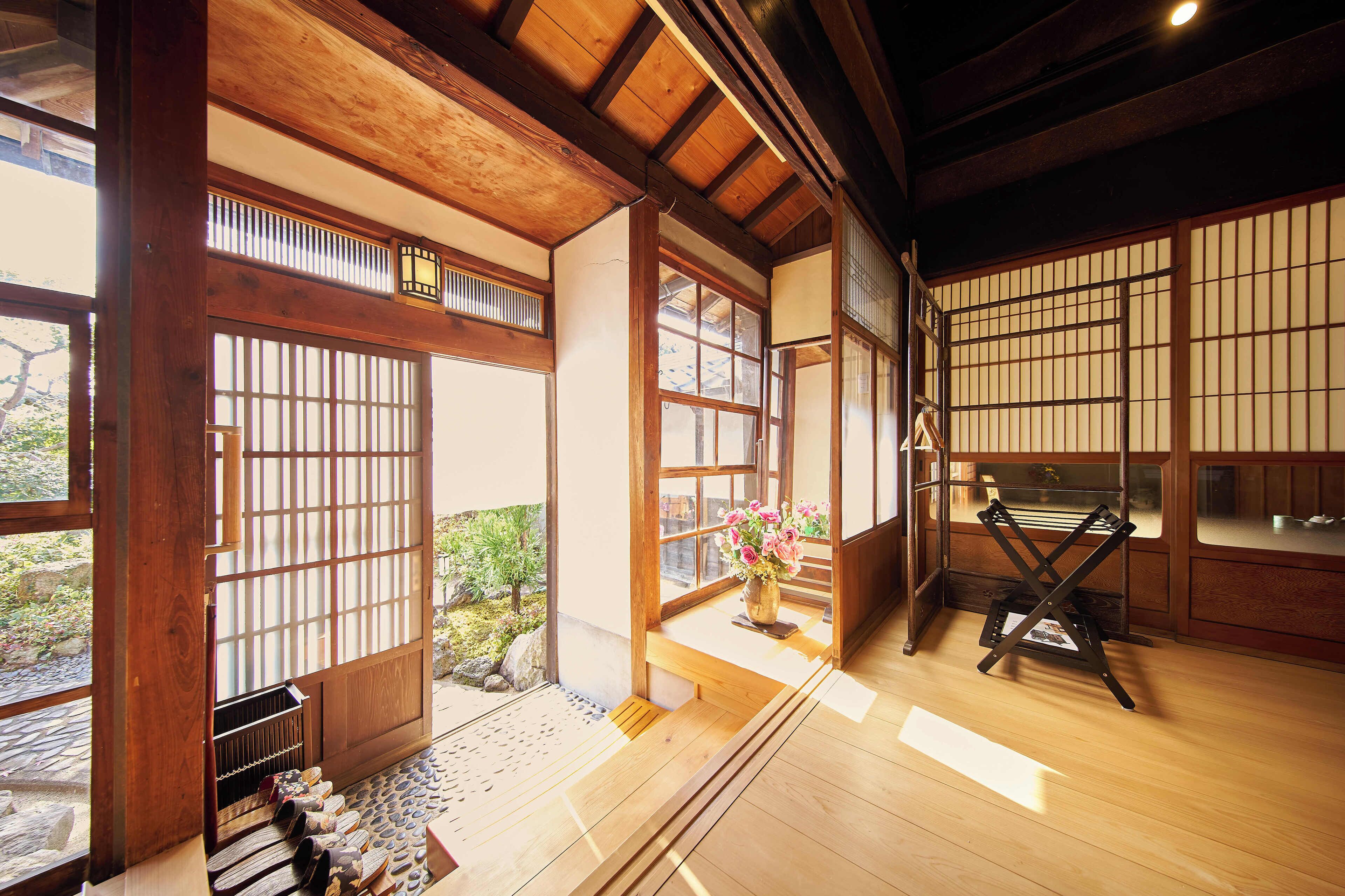 A traditional Japanese room with tatami flooring, sliding doors, and a wooden ceiling.