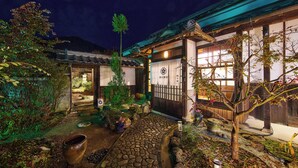 Um edifício tradicional japonês com um caminho de pedra que leva a um portão de madeira.