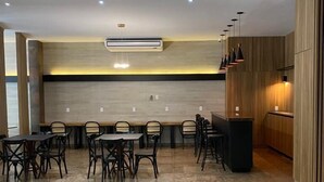 Un espace de salle à manger moderne, avec une longue table et des chaises, un appareil de climatisation et des luminaires suspendus.