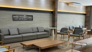 Un espace détente moderne avec un canapé gris, une table basse en bois et des fauteuils gris.