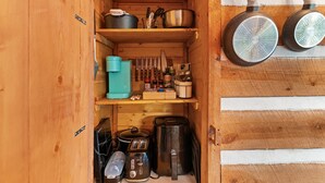 Een kleine keuken met houten planken, potten, pannen, messen en een koffiezetapparaat.
