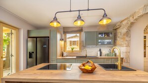 A modern kitchen with a central island, stainless steel appliances, and a stone accent wall.