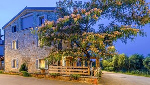 A stone building with a wooden porch and a tree with pink flowers.
