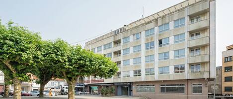 A multi-story hotel with a central courtyard, a restaurant, and a parking area.