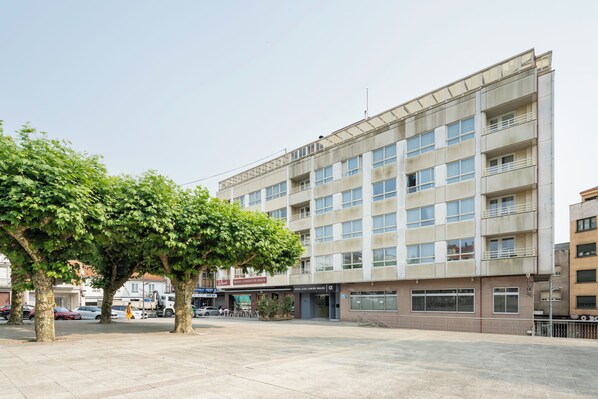Un hotel de varios pisos con un patio central, un restaurante y un estacionamiento.