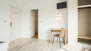 A modern, minimalistic room with a wooden desk, a chair, and a television mounted on the wall. - Alda Camiño Inglés (Ordes)