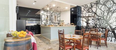 A modern kitchen with a central island, wooden chairs, and a marble floor.
