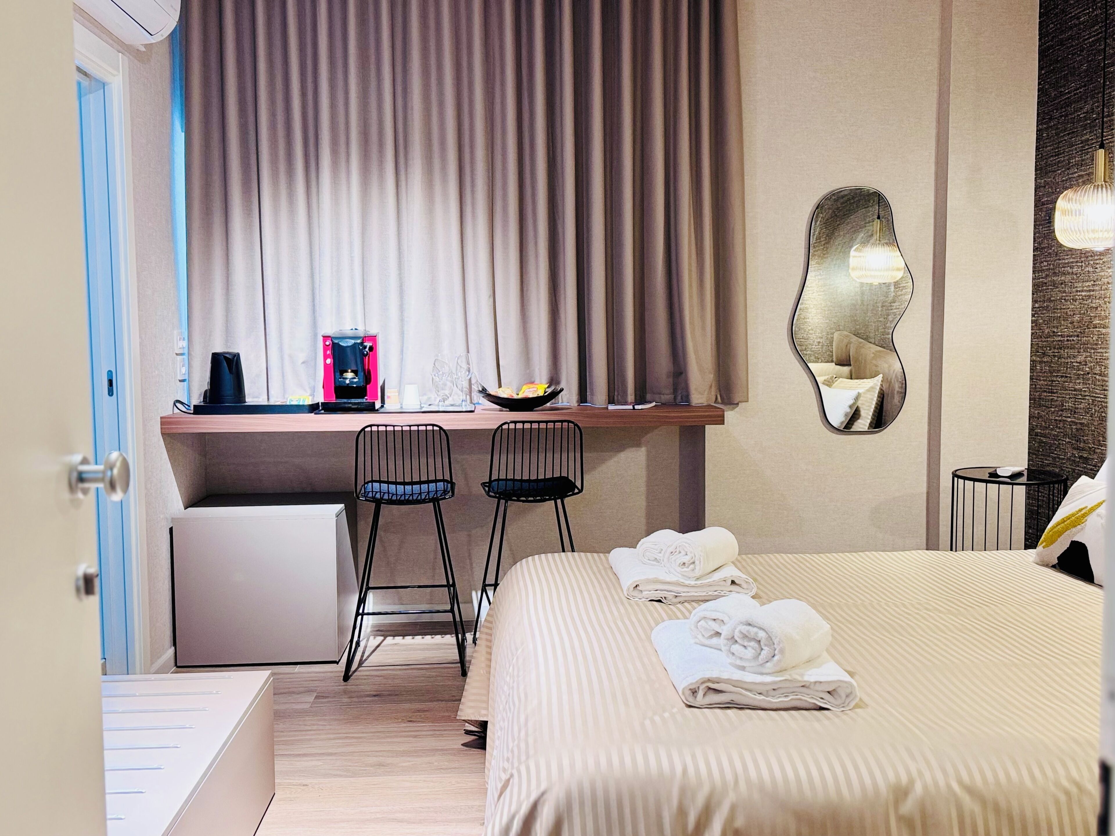 Une chambre d’hôtel avec un lit, un bureau avec deux chaises, une machine à café et un panier de fruits.