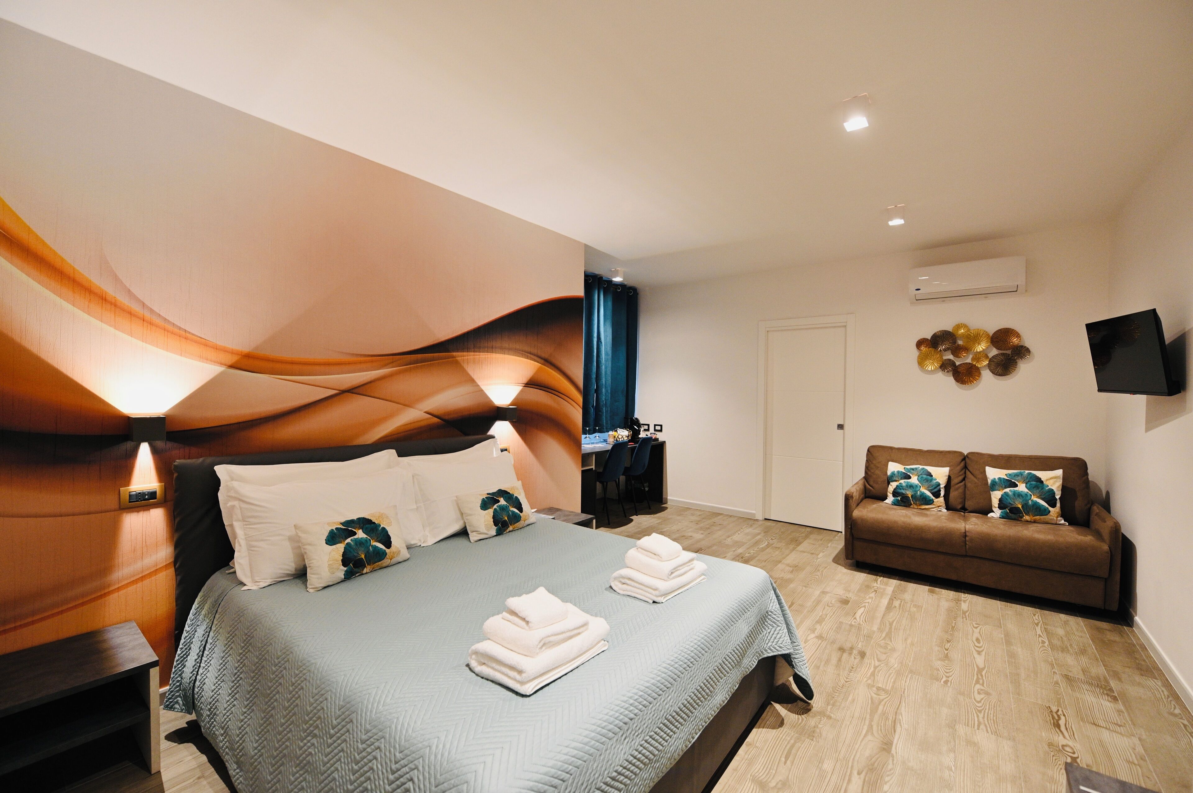 Una habitación de hotel moderna con cama, sofá, escritorio y televisor.