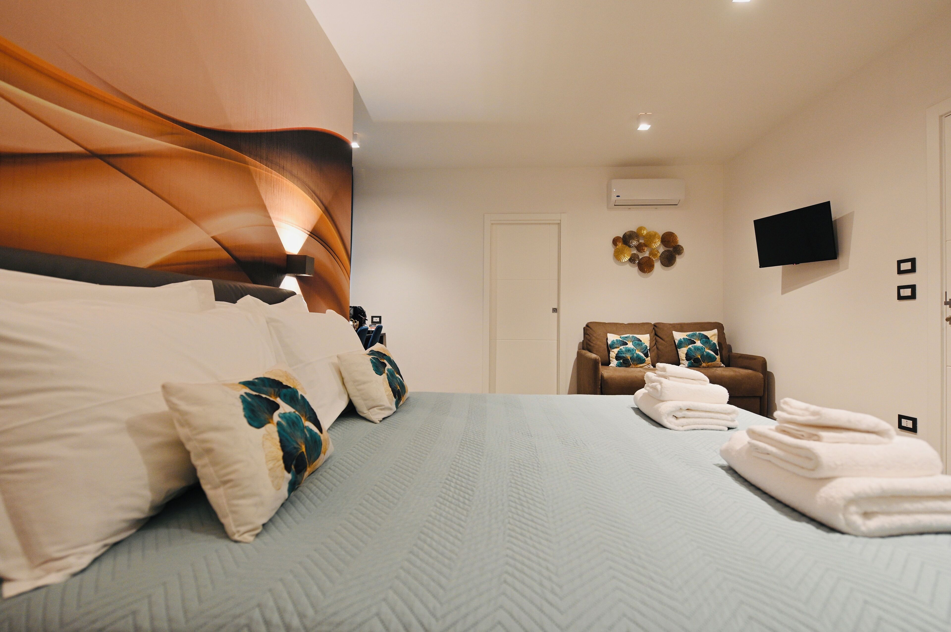 Una habitación de hotel con una cama grande, un sofá y un televisor en la pared.