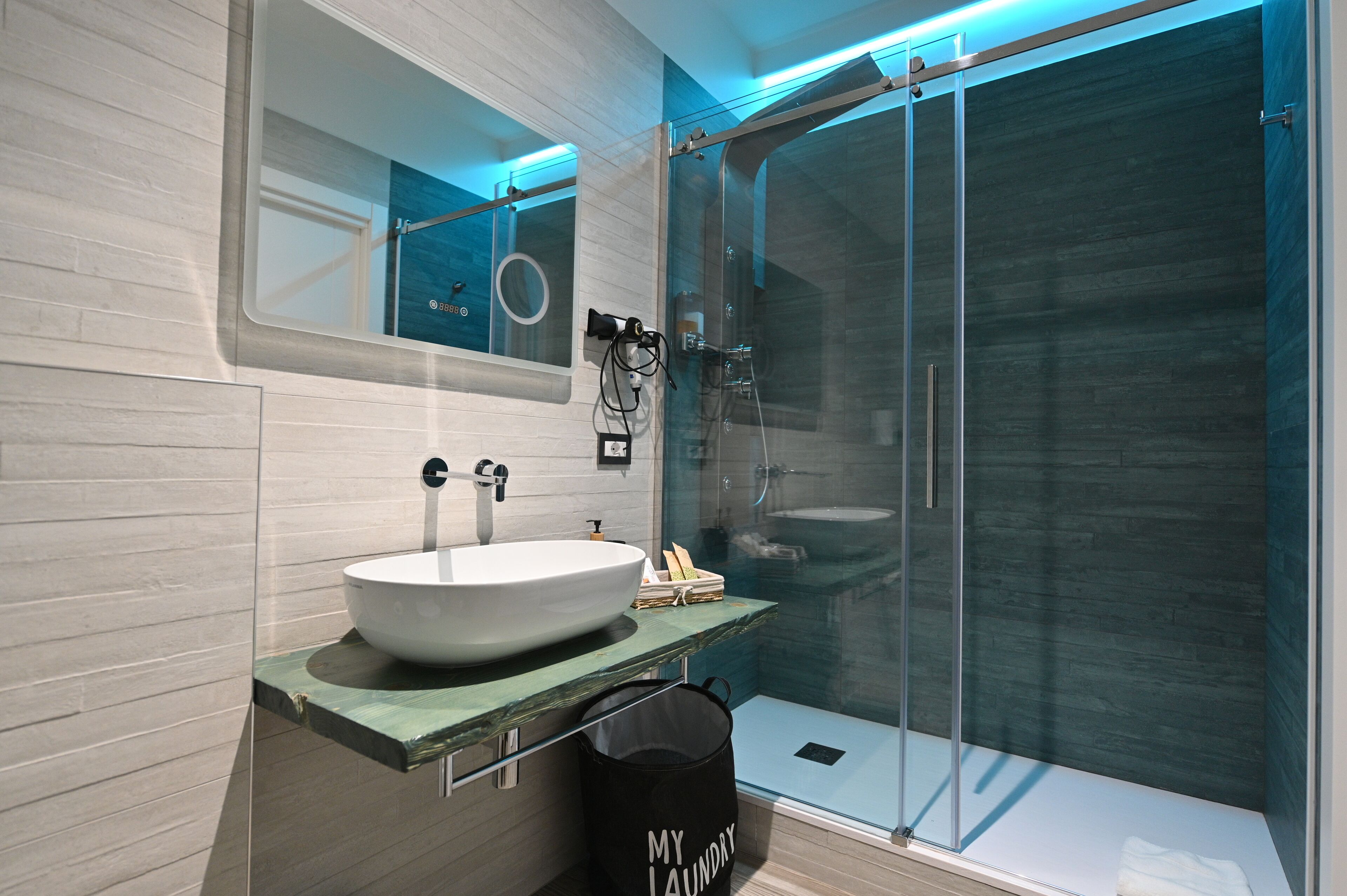 A modern bathroom with a large mirror, a vessel sink, and a glass-enclosed shower.