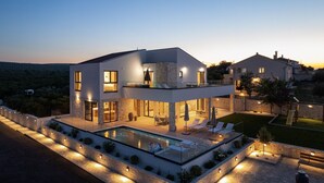 A modern two-story house with a swimming pool, outdoor seating, and a well-lit patio area. - Villa Terra & Aria Dalmatica pool sauna&jacuzzi (Sikovo)