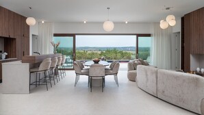 A modern kitchen with a bar area, a dining table with chairs, and a large window offering a scenic view. - Villa Terra & Aria Dalmatica pool sauna&jacuzzi (Sikovo)